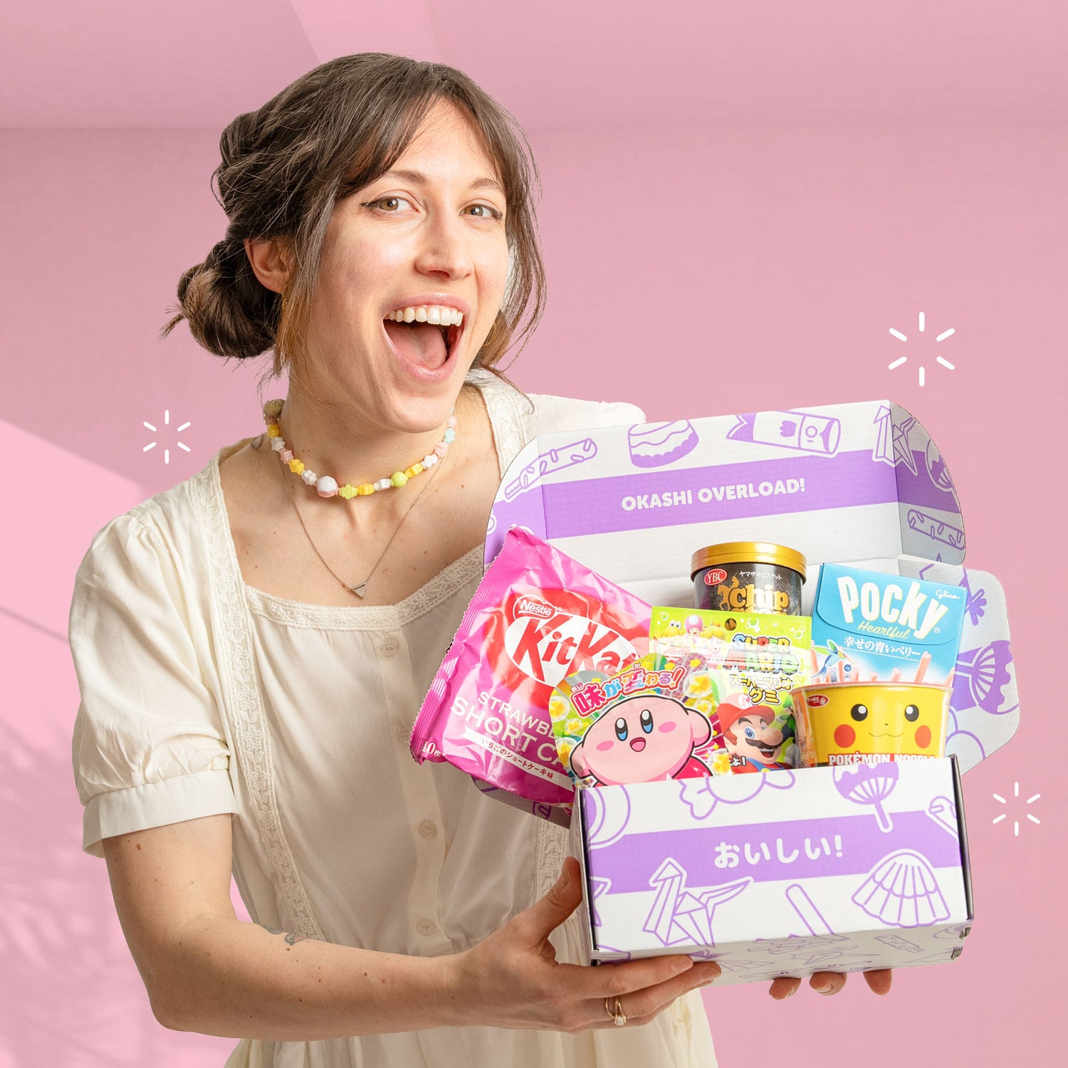 Woman holding a box of Japanese snacks against a pink background